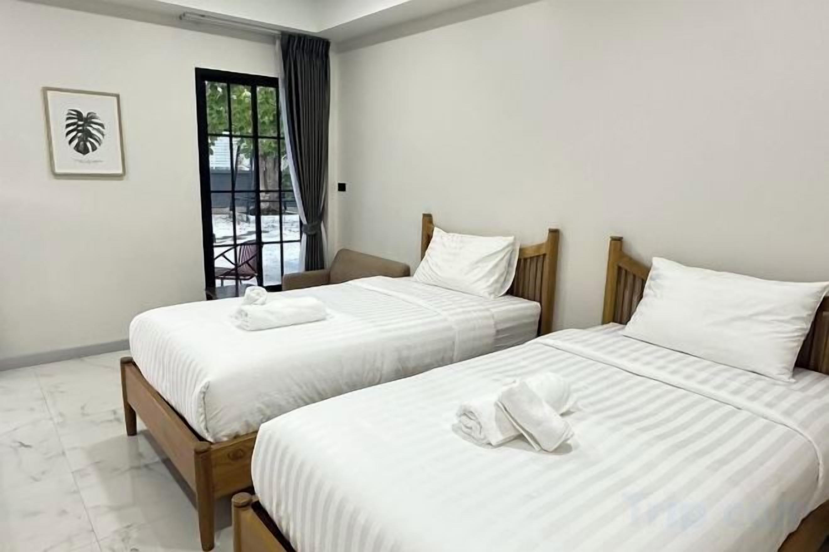 Habitación de hotel con dos camas, una puerta que da a un balcón y un cuadro en la pared.