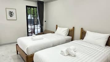 Habitación de hotel con dos camas, una puerta que da a un balcón y un cuadro en la pared.
