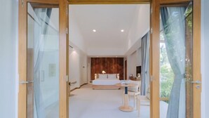 Une chambre à coucher avec un lit, une table de chevet et une vue sur l’extérieur grâce à une porte vitrée.