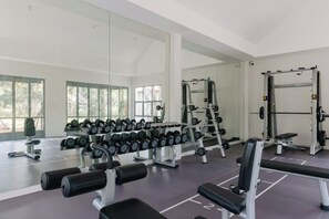 A gym with weightlifting equipment, dumbbells, and benches. - ดาวนับพัน Baan Phandao (Mae Rim)