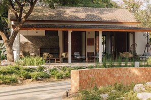 A house with a covered porch, outdoor seating, and a stone fireplace. - ดาวนับพัน Baan Phandao (Mae Rim)