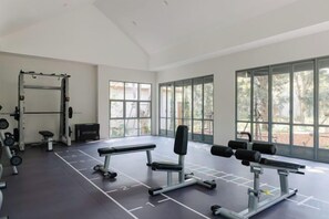 A gym with weightlifting equipment, large windows, and a high ceiling. - ดาวนับพัน Baan Phandao (Mae Rim)
