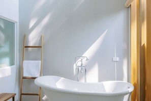 A modern bathroom with a freestanding bathtub, a wooden ladder, and a towel hanging on the wall. - ดาวนับพัน Baan Phandao (Mae Rim)