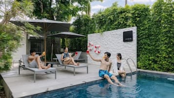 A pool area with lounge chairs and a wall-mounted sign.