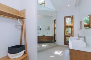 A modern bathroom with a wooden vanity, a hanging bathrobe, and a large mirror. - ดาวนับพัน Baan Phandao (Mae Rim)