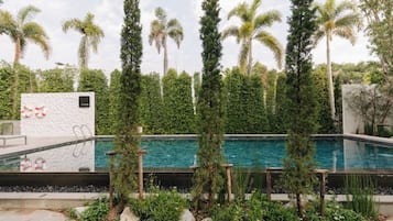 Uma piscina rodeada por palmeiras altas e vegetação exuberante.