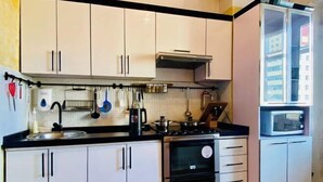 Une cuisine de taille réduite avec des meubles blancs, un plan de travail noir, une cuisinière, un four et un four à micro-ondes.
