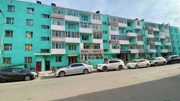 A multi-story residential building with several parked cars in front.