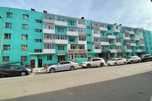 Un edifici d'apartaments de diverses plantes amb cotxes aparcats al davant.