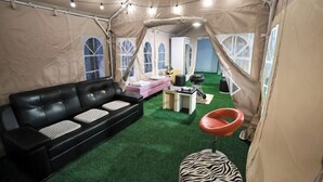 A tented room with a black leather sofa, a zebra-patterned ottoman, and a red chair. - sweetdream (Jinju)