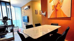 Uma sala de conferências com uma mesa de mármore, cadeiras pretas, uma televisão e um quadro na parede.