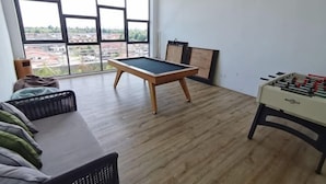 Um quarto com mesa de pebolim, mesa de bilhar e um sofá.