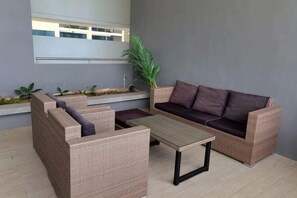 A modern outdoor seating area with wicker furniture, a flat table, and a potted plant. - Hann's Residence Stylish 3BR@MiCasa4 Home (Sibu)