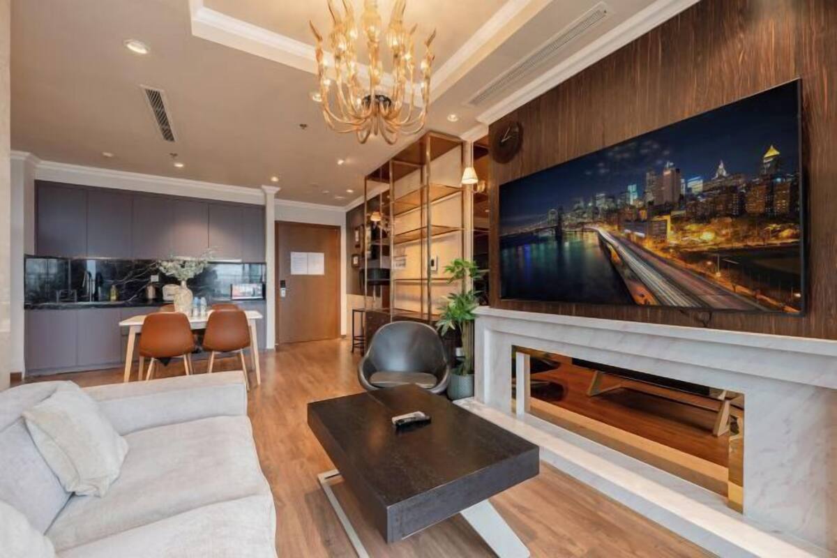 Een moderne woonkamer met een bank, een salontafel, een aan de muur bevestigde televisie en een open haard.