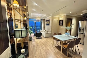 A modern interior with a dining area, kitchen, and a view of the city. - VINHOMES CENTRAL PARK LUXURY APARTMENT (Ho Chi Minh City)