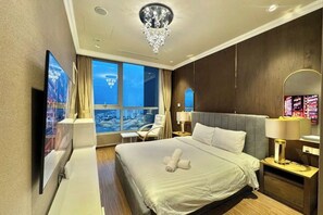 A hotel room with a large bed, a television, a window with a view, and a chandelier. - VINHOMES CENTRAL PARK LUXURY APARTMENT (Ho Chi Minh City)