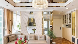 A modern hotel lobby with a sectional sofa, a chandelier, and a large window. - VINHOMES CENTRAL PARK LUXURY APARTMENT (Ho Chi Minh City)