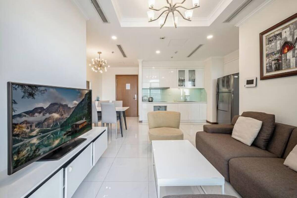 Een moderne woonkamer met een flatscreen televisie, een bank, een salontafel en een eethoek met stoelen.