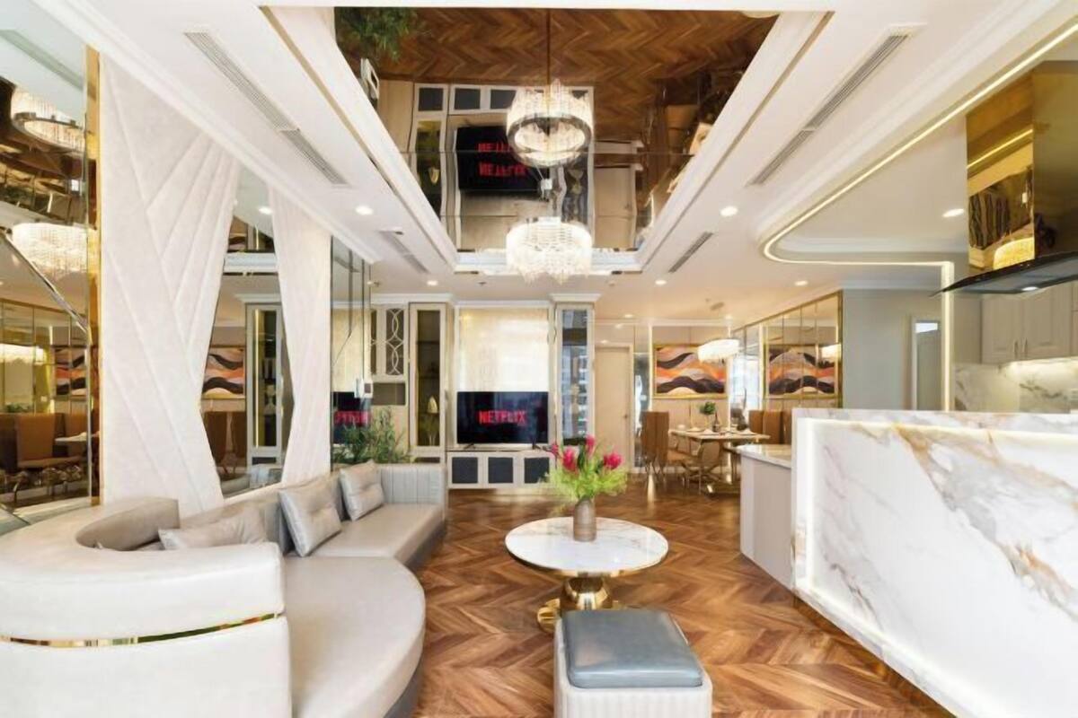 Een moderne hotellobby met een centrale zithoek, een kroonluchter en een tv-scherm waarop 'NETFLIX' staat.