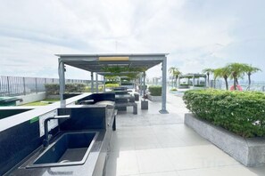 Sitzgelegenheiten im Freien mit einem Brunnen, einem überdachten Bereich und Blick auf das Meer.