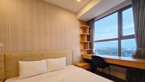Een hotelkamer met een groot bed, een bureau en uitzicht door een raam.