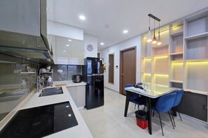 Une cuisine moderne avec un réfrigérateur noir, une table à manger avec des chaises bleues et un four encastré.