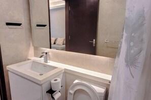 A modern bathroom with a white sink, toilet, and a large mirror above the sink. - Damas Mont Kiara by Scape Stay (Kuala Lumpur)