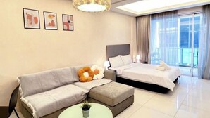 A hotel room with a sofa, a bed, a small table, and a ceiling light fixture. - Damas Mont Kiara by Scape Stay (Kuala Lumpur)