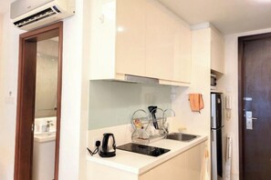 A compact kitchen with white cabinets, a built-in oven, and a refrigerator. - Damas Mont Kiara by Scape Stay (Kuala Lumpur)