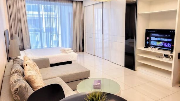 A modern hotel room with a bed, sofa, TV, and a glass coffee table. - Damas Mont Kiara by Scape Stay (Kuala Lumpur)