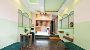 Un área de recepción con una paleta de colores verde y blanco, un mostrador de recepción, una zona de estar con un banco y una escalera que conduce a un nivel superior.