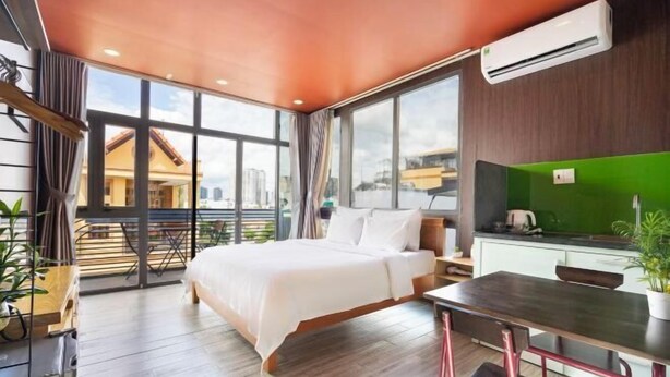 Una habitación de hotel moderna con una cama grande, una mesa de comedor y una kitchenette.