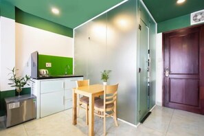 Una cocina compacta con refrigerador, lavamanos y una mesa de comedor con sillas.