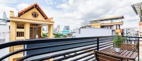 A balcony with a railing, a wooden bench, and a potted plant.