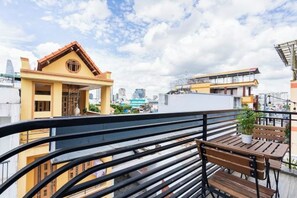 A balcony with a wooden bench and a potted plant, overlooking a cityscape with buildings and a clear sky. - Gemini Saigon Center - New & Quiet Near Bui Vien Walking Street (Ho Chi Minh City)