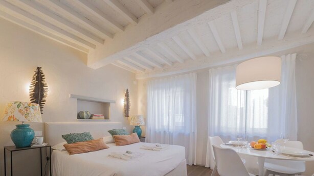 A bedroom with a bed, bedside tables, a desk with chairs, and a dining table set for two. - City / Village Apartment in Cortona with 1 bedrooms sleeps 2 (Cortona)