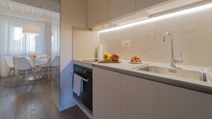 A modern kitchen with a built-in oven, a sink, and a dining area with a table and chairs. - City / Village Apartment in Cortona with 1 bedrooms sleeps 2 (Cortona)