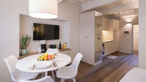 A modern kitchen with white cabinets, a flat-screen TV, and a dining area with a round table and white chairs. - City / Village Apartment in Cortona with 1 bedrooms sleeps 2 (Cortona)