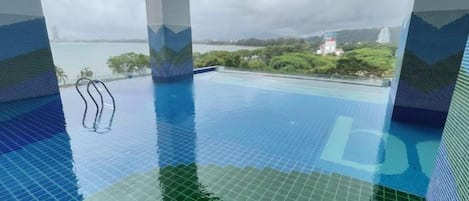 An indoor swimming pool with a view of a body of water and distant landscape.