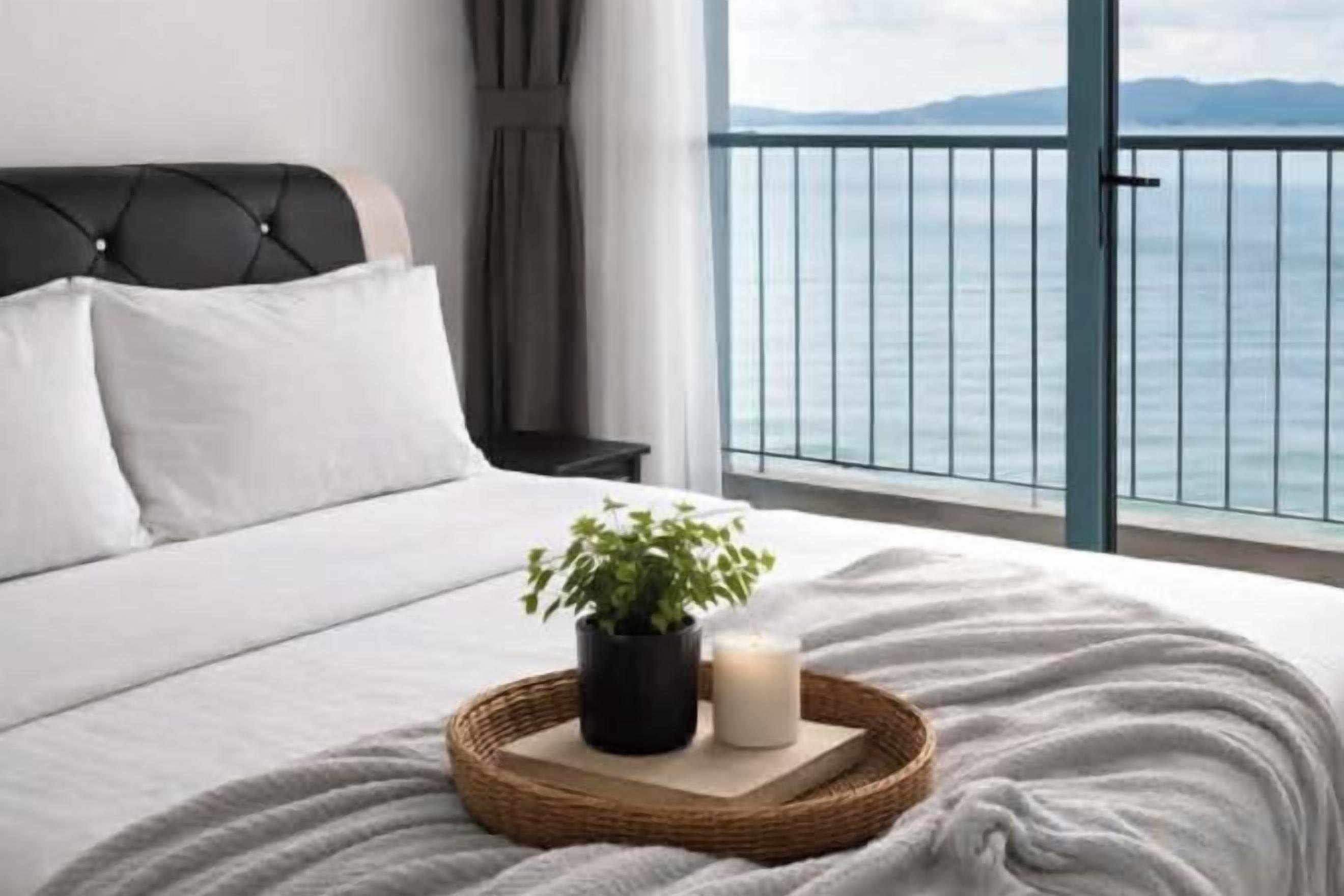 A bedroom with a bed, a nightstand, a potted plant, and a candle on a tray.