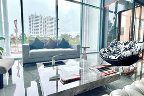 Una sala de estar moderna con un sofá, una silla estampada en blanco y negro y una mesa de centro de mármol.