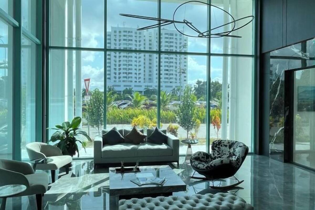 A modern interior with a large window, a sofa, a coffee table, and a patterned armchair.