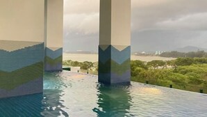 Une piscine à débordement offrant une vue sur une étendue d’eau et un paysage lointain.