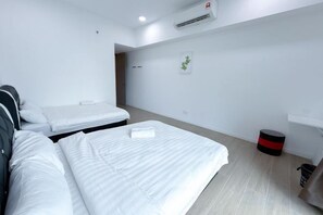 A hotel room with two beds, a small table, a trash bin, and a wall-mounted air conditioner. - Baysuites Near Sicc (Kota Kinabalu)
