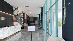 Un espace d’accueil d’hôtel avec un comptoir en marbre, un panneau indicateur et un coin salon.