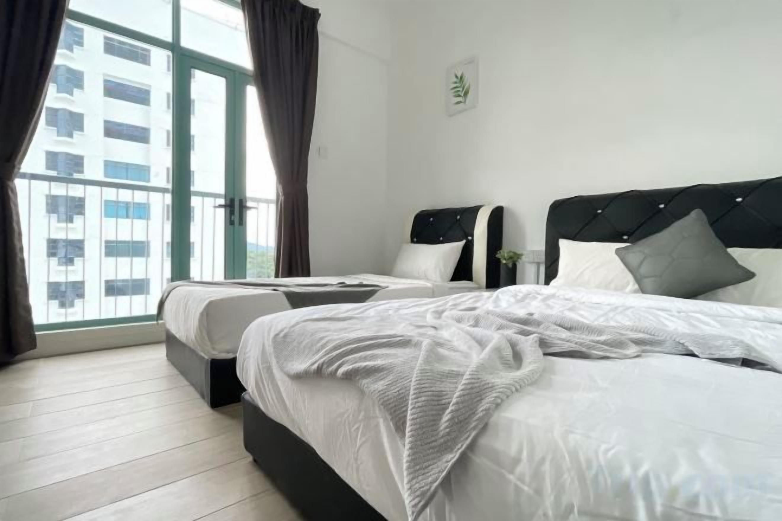 A hotel room with two beds, a large window with curtains, and a view of buildings outside.