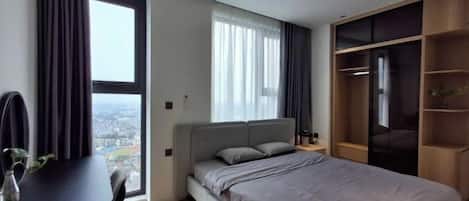 Een slaapkamer met een bed, een bureau en een groot raam.