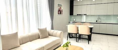 A modern living room with a sofa, a coffee table, and a dining area with chairs.
