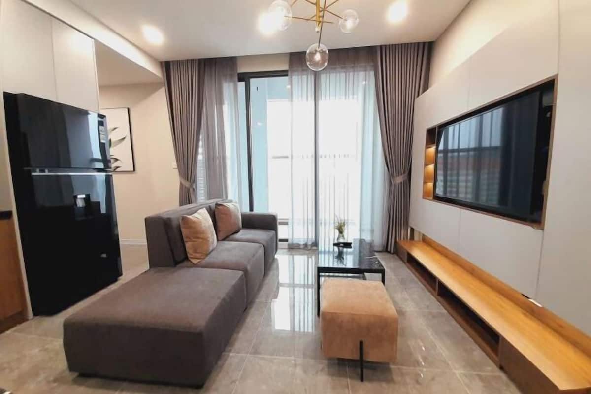 A modern living room with a sofa, ottoman, TV, and a glass coffee table.