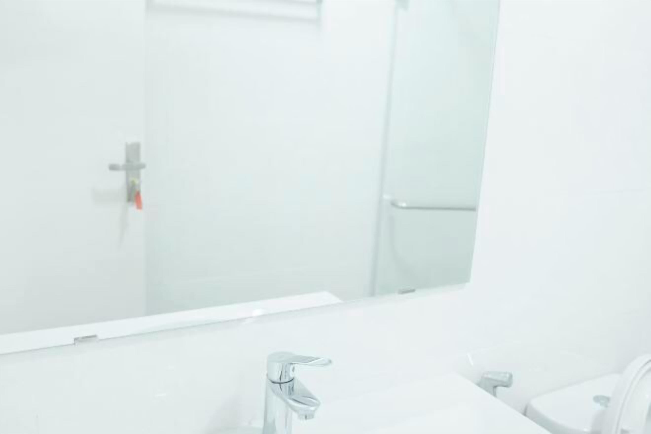 Un baño con espejo, lavamanos e inodoro.